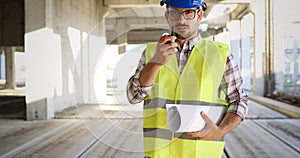 Male architect communicating on walkie-talkie at site