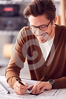 Male Architect At Desk In Office Amending Building Plans