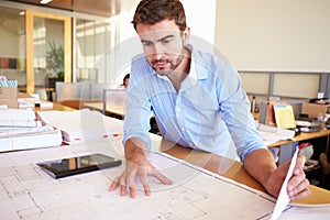 Male Architect With Digital Tablet Studying Plans In Office