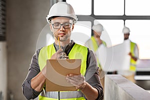 male architect in helmet with clipboard at office