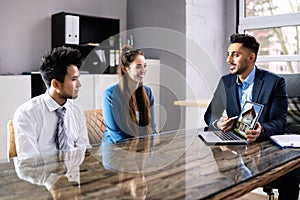 Male Architect Showing House Model On Laptop To Couple