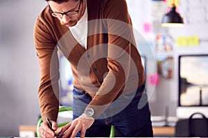 Male Architect Standing At Desk In Office Amending Building Plans