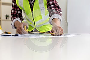 The male architect uses a tape measure to measure the house designs.