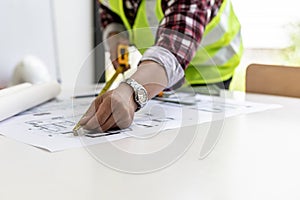 The male architect uses a tape measure to measure the house designs, he is checking the house plans that he has designed before