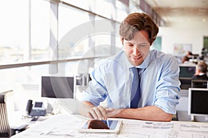 Male architect using tablet computer at a desk in an office photo