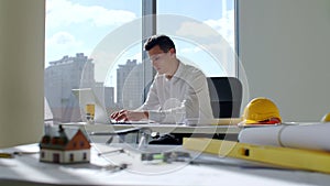 Male architect working with drawings and computers at table