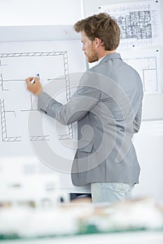 Male architect writing in whiteboard