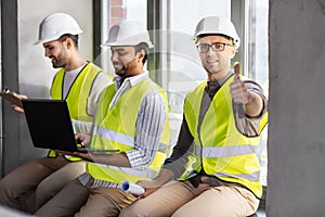 male architects in helmets working at office