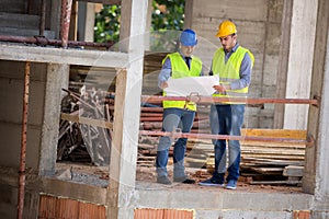 Male architects look at blue print on building construction