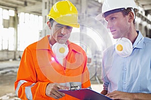 Male architects in protective workwear discussing at construction site