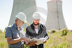 Male architects reviewing documents together at electric power