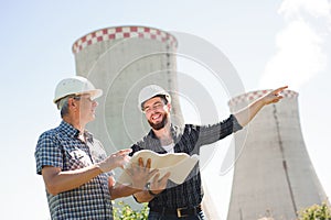 Male architects reviewing documents together at electric power