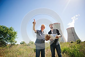 Male architects reviewing documents together at electric power plant.