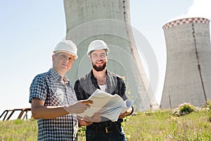 Male architects reviewing documents together at electric power plant.