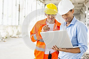 Male architects using laptop at construction site photo