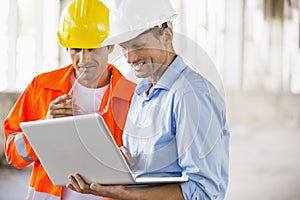 Male architects working on laptop at construction site