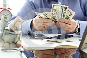 Male arms counting big amount of US currency at worktable