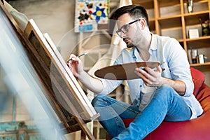 Male art school artist painting with oil on canvas