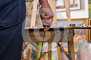 Male artist hand holding a tiny paintbrush