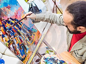 Male Artist Working On Painting In Bright Daylight Studio