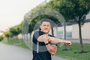 Male asian athlete, kneading shoulder pain, sore arm muscles in the park