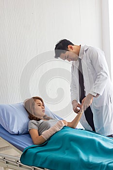 Male Asian doctor checked the patient`s pulse to check the abnormalities of the heart in bed