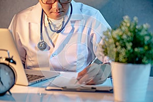 Male Asian doctor working with laptop and clipboard in hospital