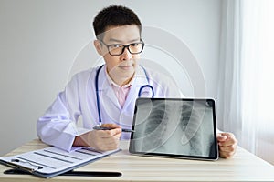Male asian doctor working in the office hospital. discussing x-ray by using digital tablet. healtcare and assistance concept