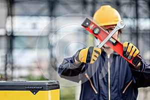 Worker man holding level tool and wrench at site