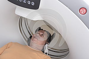 A male asian patient undergoes a CT scan at the clinic photo
