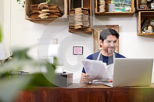 Male Assistant Working On Laptop Behind Sales Desk Of Florists Store photo