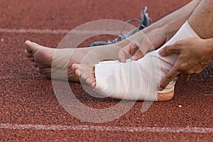 Male athlete applying compression bandage onto ankle injury of a football player