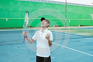 male athlete clenching fist celebrating victory by holding racket