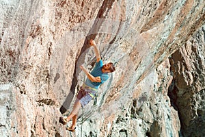 Male Athlete climbing severe overhanging high orange Rock