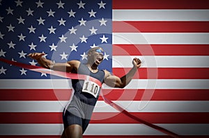 Male athlete crossing finish line against American flag