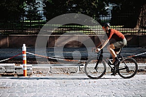 Male athlete cycling on black bike on empty city street