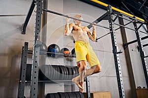 Male athlete doing pull-ups at the gym