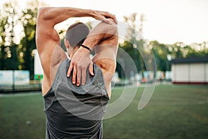 Male athlete doing stretching exercise, back view