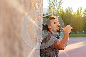 Male athlete drinking or taking his dose of whey protein, bcaa, creatine, casein or energy drink, after a hard workout outside at