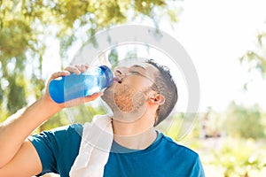 Male Athlete Drinking Water After Workout In Park