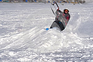 A male athlete engaged in snow kiting on the ice of a large snowy lake. He goes skiing in the snow.