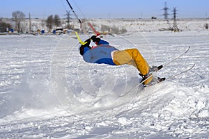 A male athlete engaged in snow kiting on the ice of a large snowy lake. He performs the jump. Winter sunny frosty day.