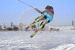 A male athlete engaged in snow kiting on the ice of a large snowy lake. He performs the jump. Winter sunny frosty day.