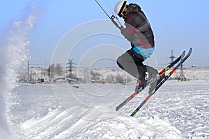 A male athlete engaged in snow kiting on the ice of a large snowy lake. He performs the jump. Winter sunny frosty day.