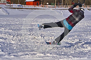 A male athlete engaged in snow kiting on the ice of a large snowy lake. He performs the jump. Winter sunny frosty day. Close-up