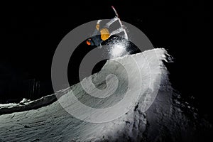 Male athlete jumping on snowboard, against the background of dark sky