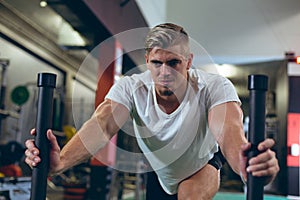 Male athlete pushing prowler sled in fitness studio