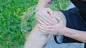 Male athlete runner touching foot in pain due to sprained ankle. unrecognizable athlete sits on the ground and suffers