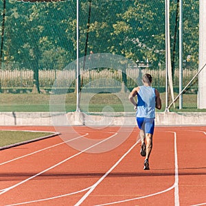 Male athlete running along an athletic track on the stadium