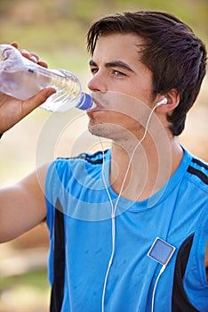 Male athlete, running and water break with earphones, nature and hiking for fitness and wellness. Marathon runner, for